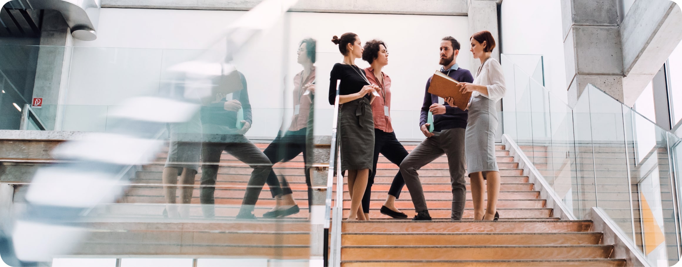 Männer und Frauen unterhalten sich auf der Treppe eines Bürogebäudes.