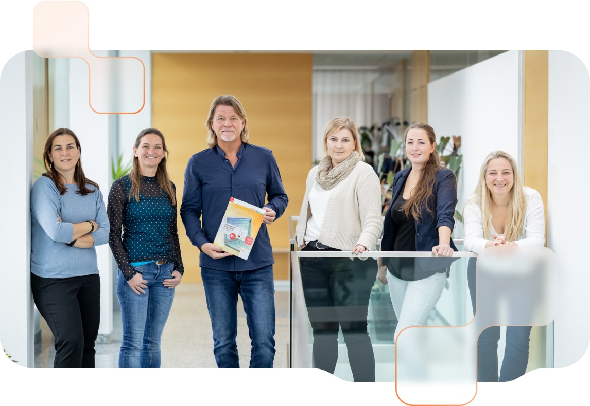 Grppenfoto des BMD Schulbuchteams im BMD Gebäude - Projektleiter Franz Mitterbaur hält das BMD Schulbuch in den Händen