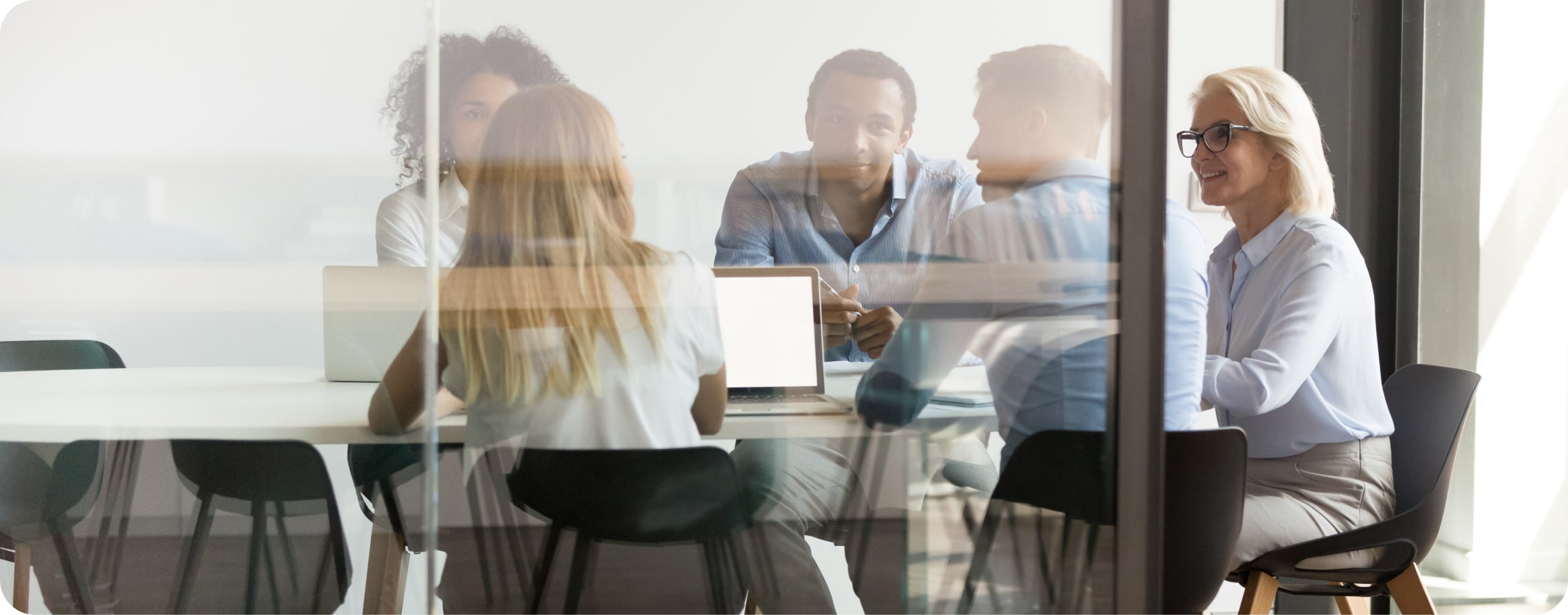 Männer und Frauen sitzen für ein Meeting am Tisch.