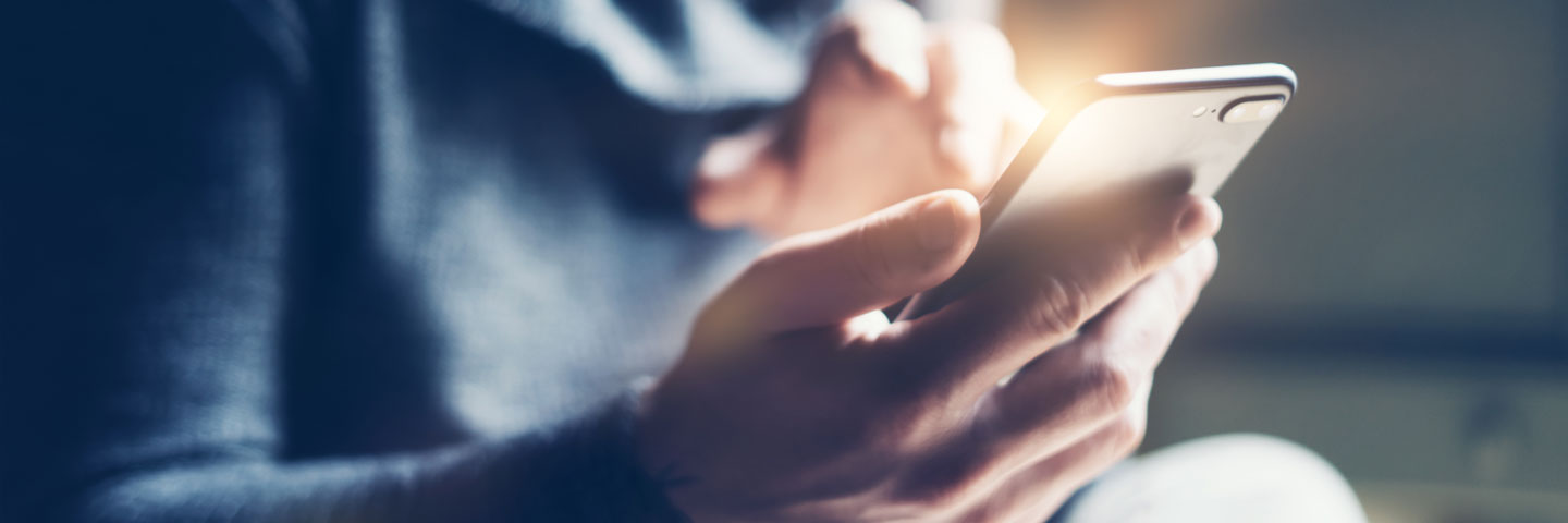 Nahaufnahme einer Person, die ein Smartphone in der Hand hält und den Bildschirm mit einer Hand bedient.