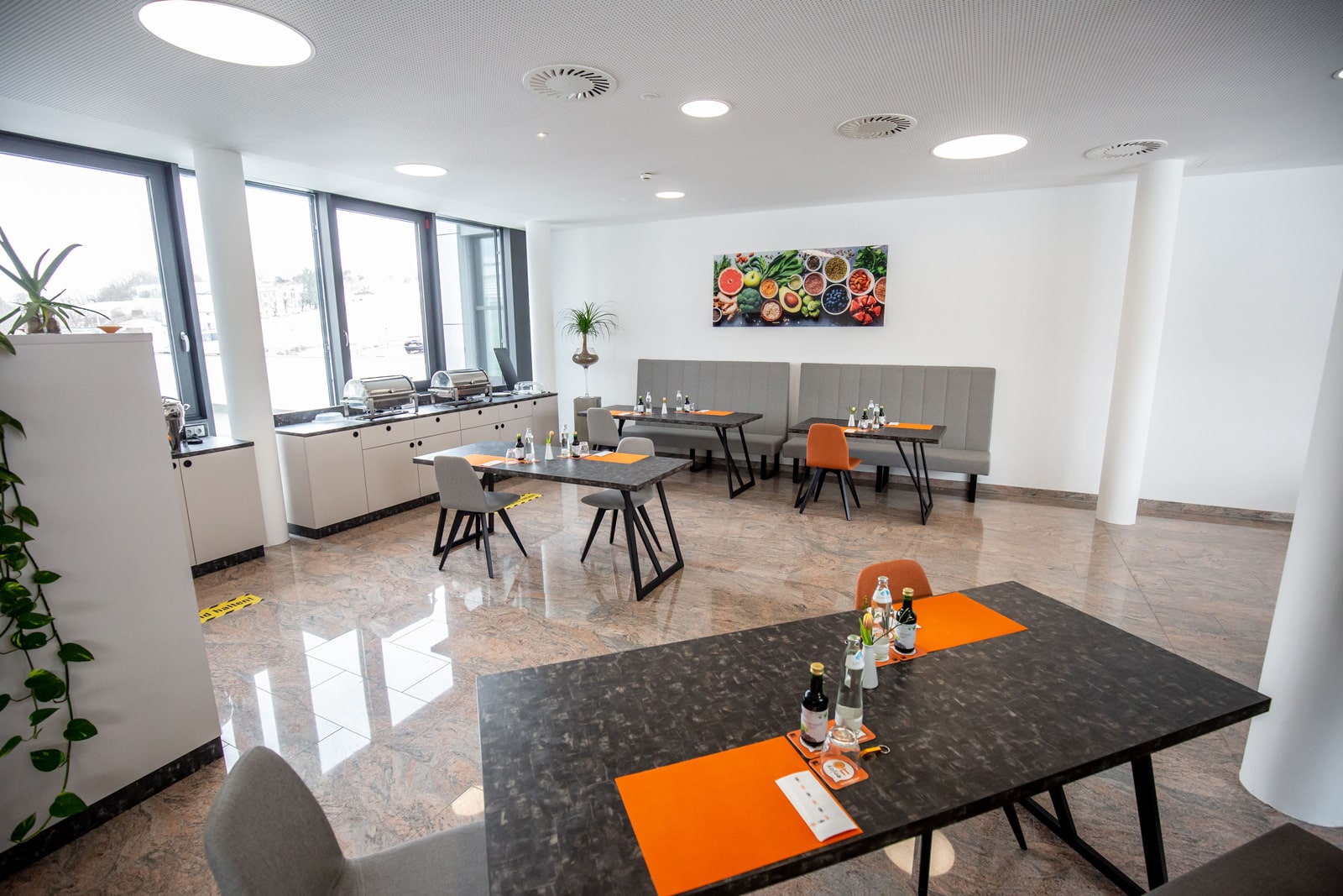 Essensbereich mit Tischen, Platzsets, Wasserkaraffen und einem Buffetbereich für Seminar-Verpflegung.