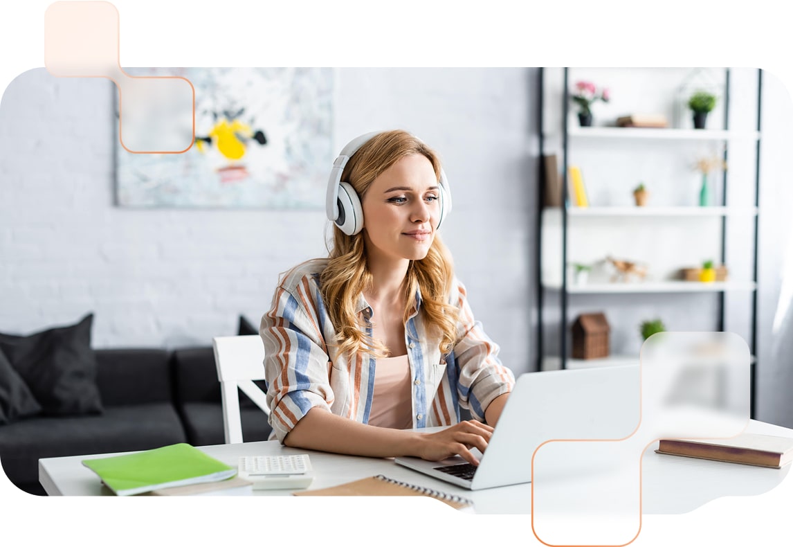 Person trägt Kopfhörer und arbeitet an einem Laptop an einem Schreibtisch mit Arbeitsmaterialien, umgeben von einer gemütlichen und modernen Umgebung.