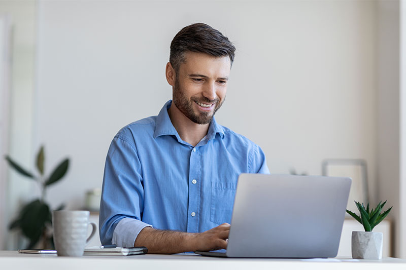 Foto von einem Mann im hellblauen Shirt vor dem Laptop