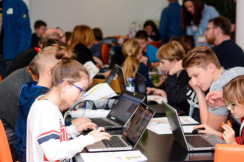 Viele Kinder die sehr eifrig an vielen Laptops arbeiten