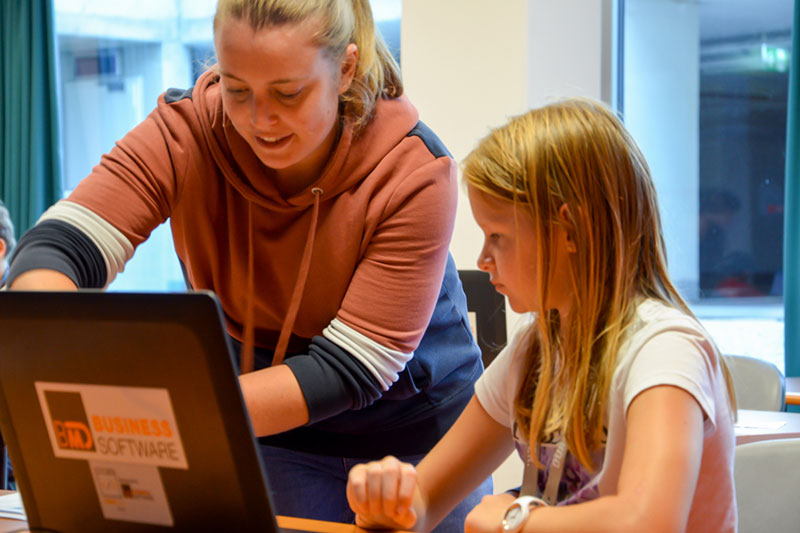 Eine BMD Mitarbeiterin erklärt das Programmieren im Rahmen der KinderUni