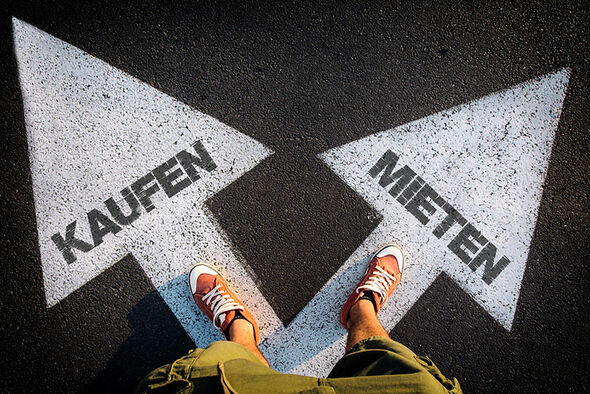 Das Bild zeigt die Füße einer Person, stehend auf einem Doppelpfeil. Die Pfeilspitzen ragen in unterschiedliche Richtungen und beinhalten die Texte "Kaufen" und "Mieten". [Foto © stock.adobe.com - Itummy]