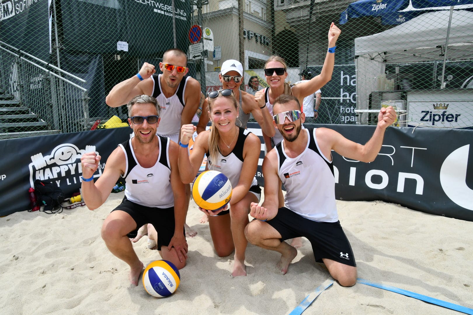 Ein Team ist am Volleyballplatz und freut sich.
