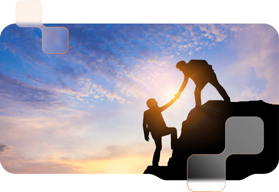 Silhouette of two people on a mountain top at sunset, one person helping the other to climb up.